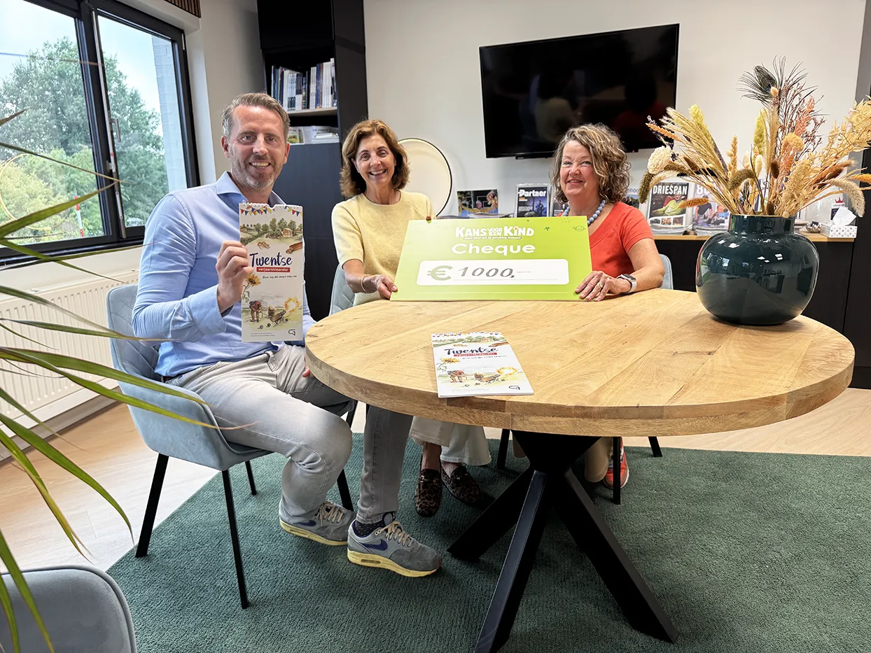 Uitreiking cheque aan Kans voor een Kind voor verkoopopbrengst Twentse verjoarskleander. Links Laurens Oude Elberink, midden Els Bos, rechts Anne Winkelhuis.